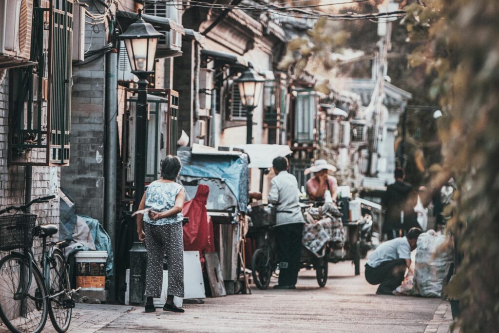 A glimpse into the vibrant street life of a traditional hutong in Beijing, China, showcasing daily interactions.